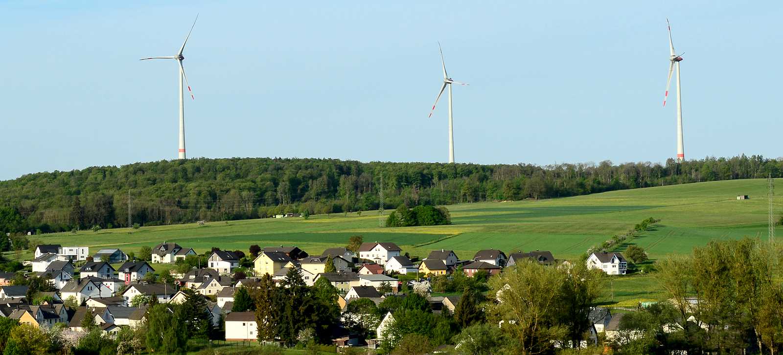 3 Windräder hinter einer Gemeinde